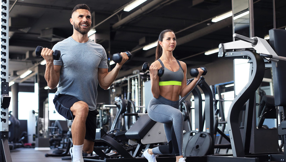A fit man and woman work out side-by-side in an apartment fitness facility.