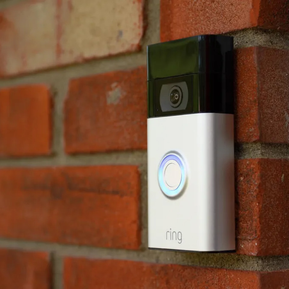 A RING smart doorbell with camera on a brick wall.
